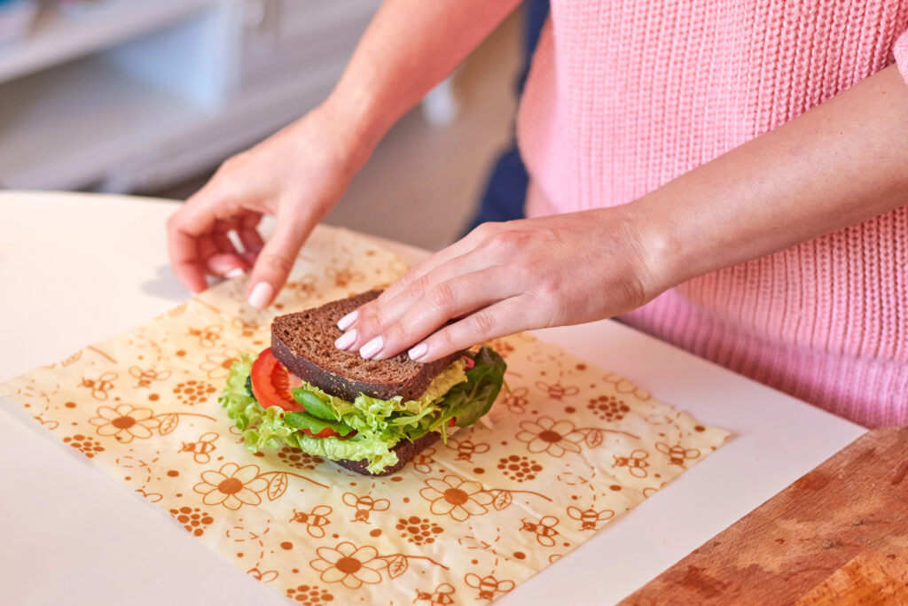 Bees wrap alternative to plastic wrap, being used to wrap a sandwich.