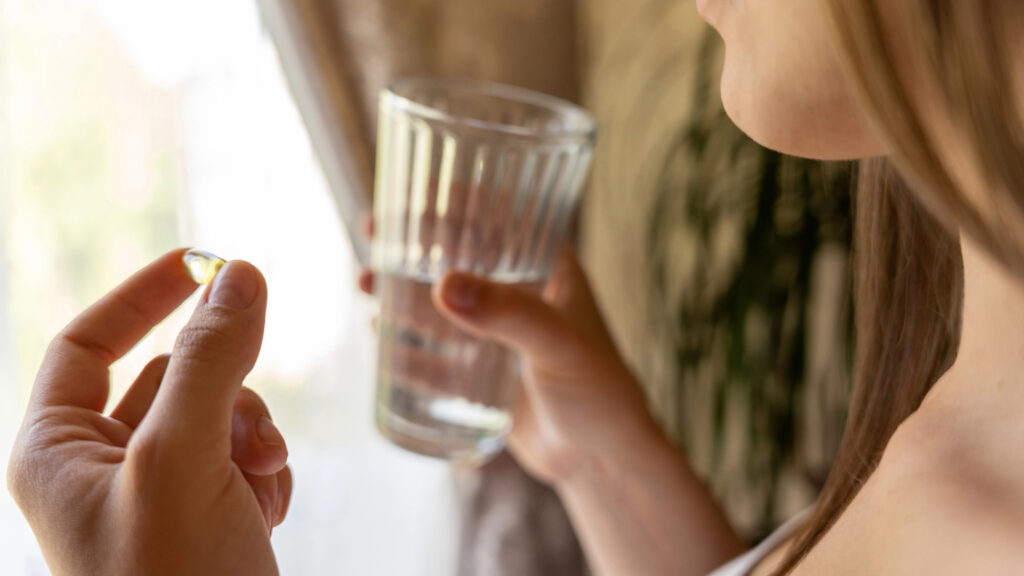 Woman taking a vitamin with a glass of water.